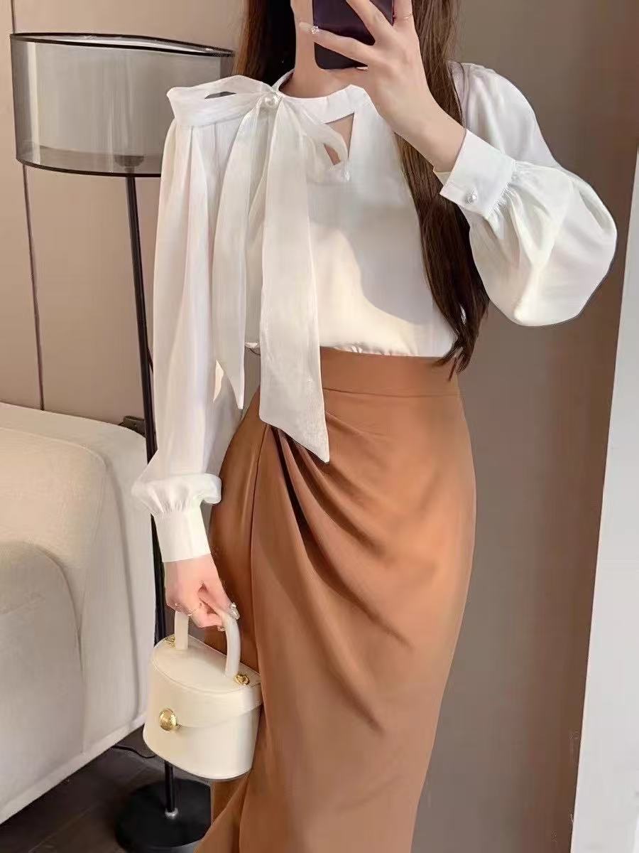 long-sleeved blouse with a stand collar and a delicate bow accent at the neckline, paired with a stylish wrap