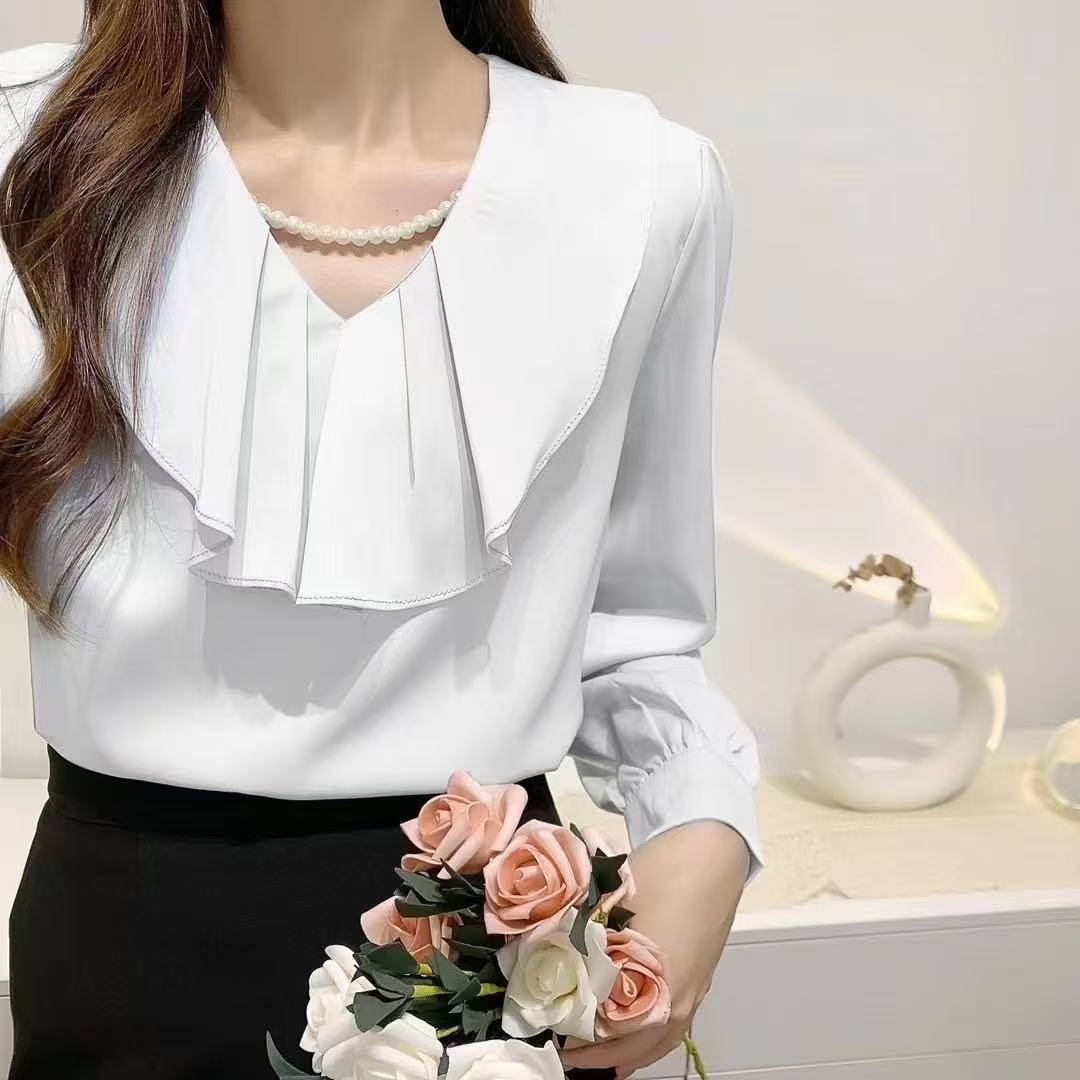 blouse with a ruffled collar and a pearl necklace.