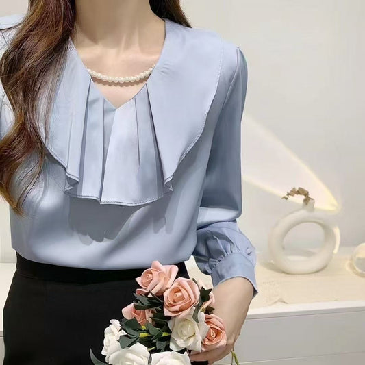 blouse with a ruffled collar and a pearl necklace.