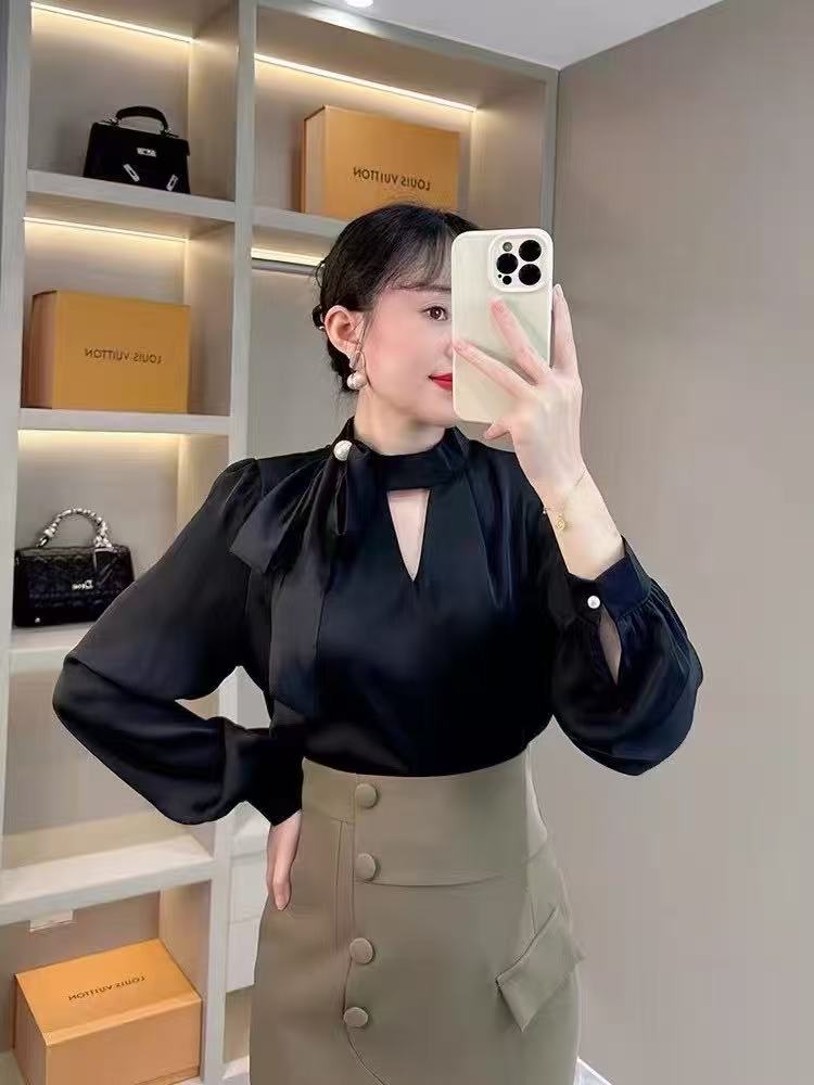 long-sleeved blouse with a stand collar and a delicate bow accent at the neckline, paired with a stylish wrap