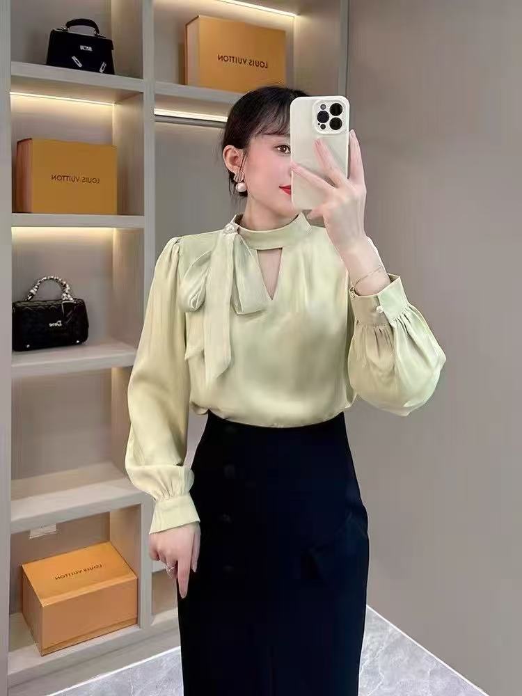 long-sleeved blouse with a stand collar and a delicate bow accent at the neckline, paired with a stylish wrap