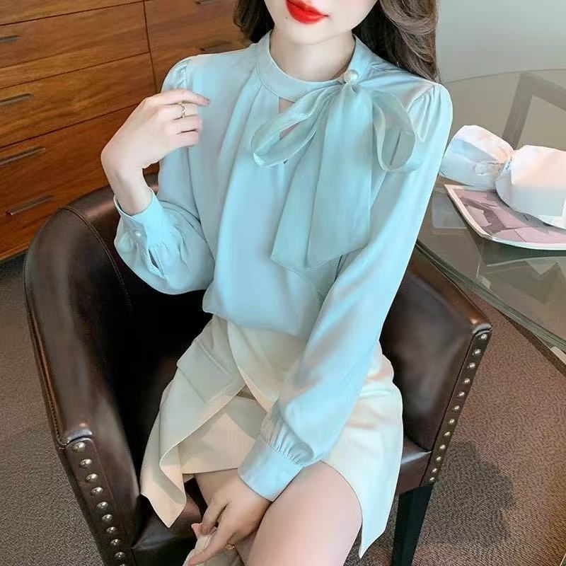 long-sleeved blouse with a stand collar and a delicate bow accent at the neckline, paired with a stylish wrap