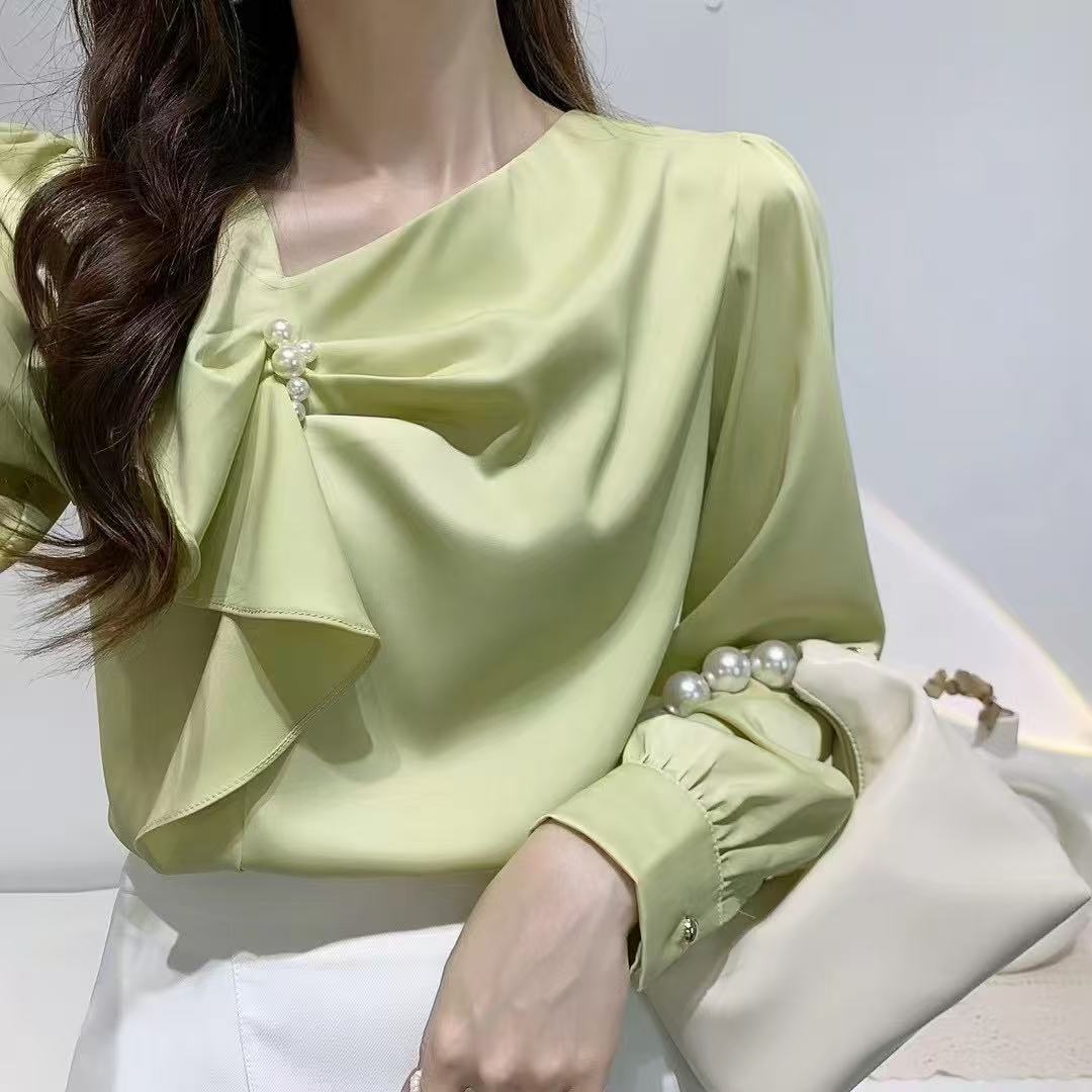 ruffled blouse with pearl.blouse has long sleeves and gathered accents on the chest, along with a pearl embellishment near the neckline.