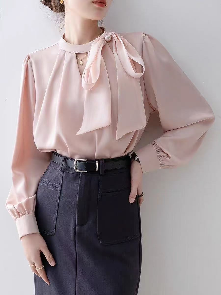long-sleeved blouse with a stand collar and a delicate bow accent at the neckline, paired with a stylish wrap