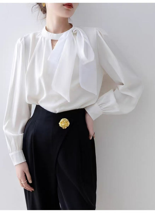 long-sleeved blouse with a stand collar and a delicate bow accent at the neckline, paired with a stylish wrap
