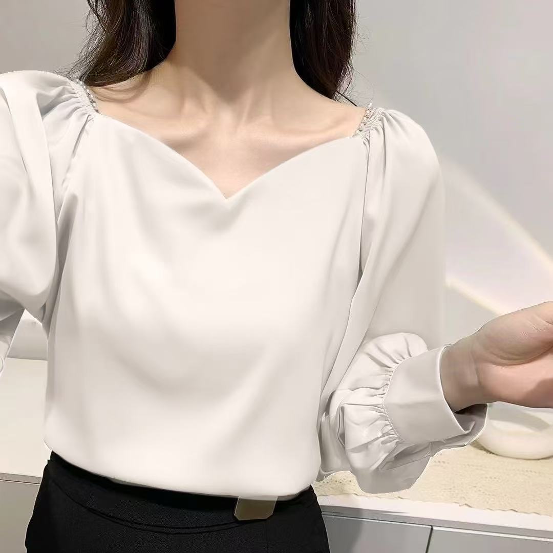 satin blouse, perfect for a vintage or office-casual Korean-inspired look, features a V-neckline with delicate pearl detailing at the shoulders and stylish gathered or ruffled long sleeves.