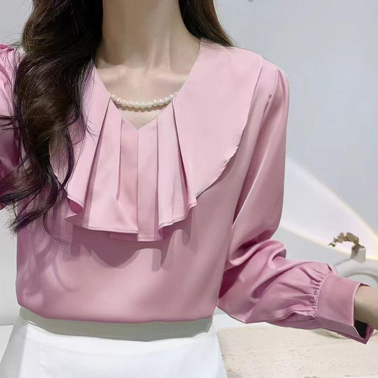 blouse with a ruffled collar and a pearl necklace.